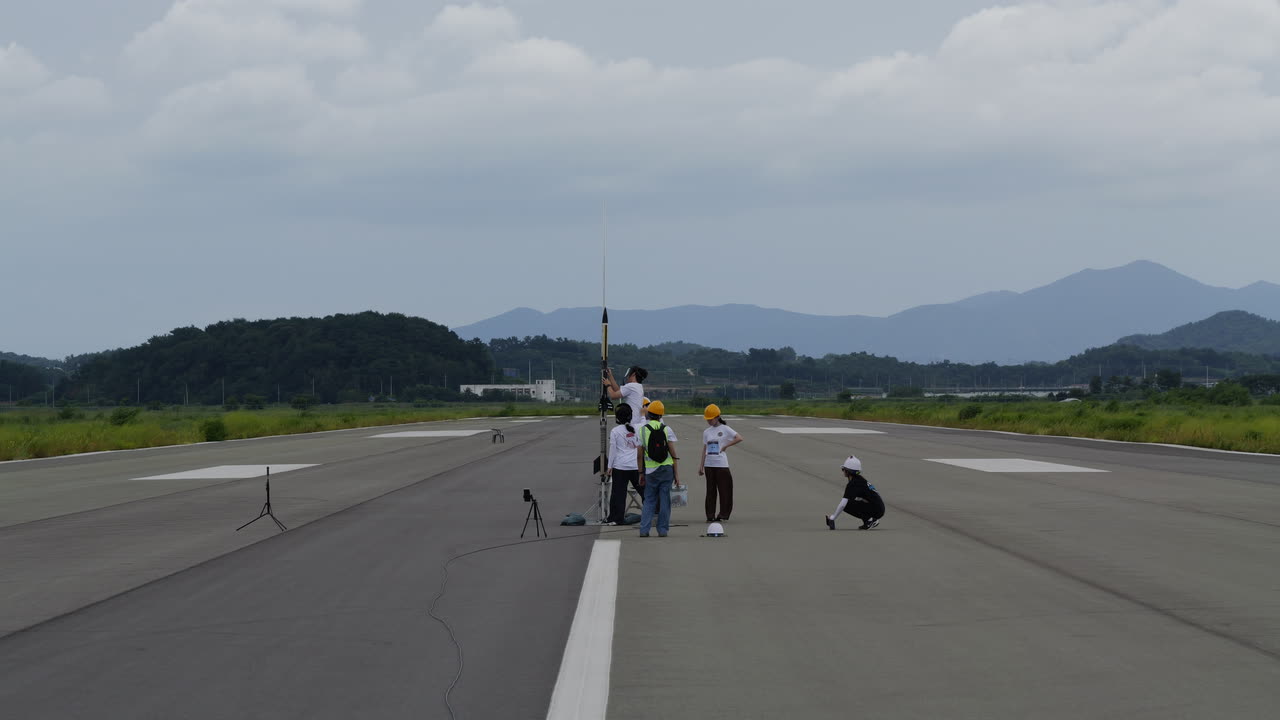 The team around IDENTITY&sup2; on the launch rail, on the runway at NURA 2026, ridgelines behind