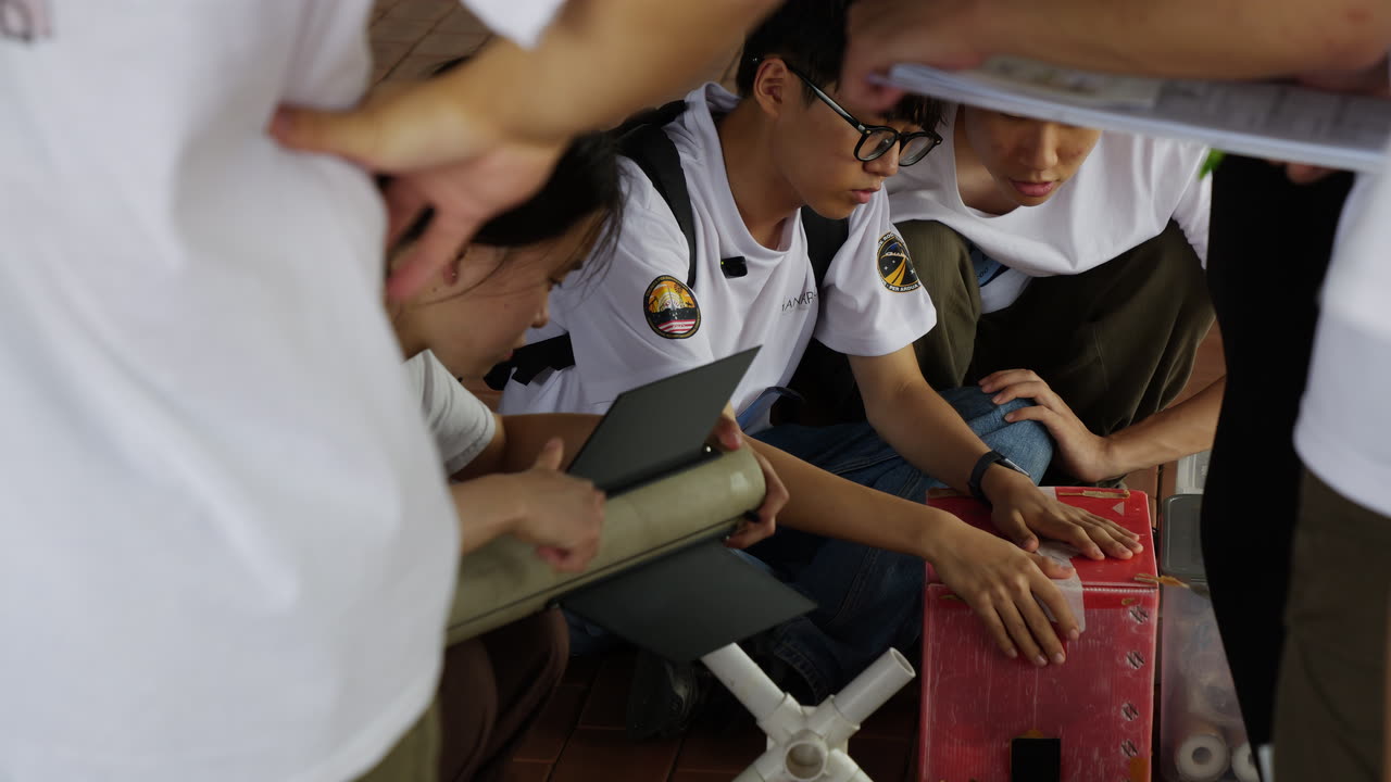 Team members crouched around an airframe section, a laptop and a checklist, working through pre-flight